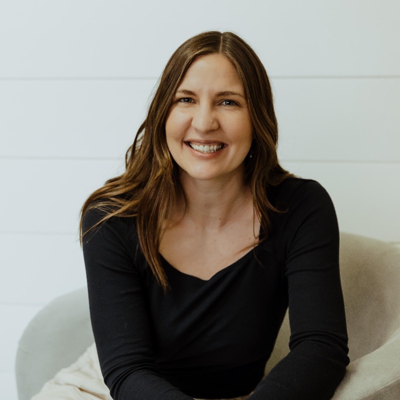 woman in a black long sleeve tee smiling in a char