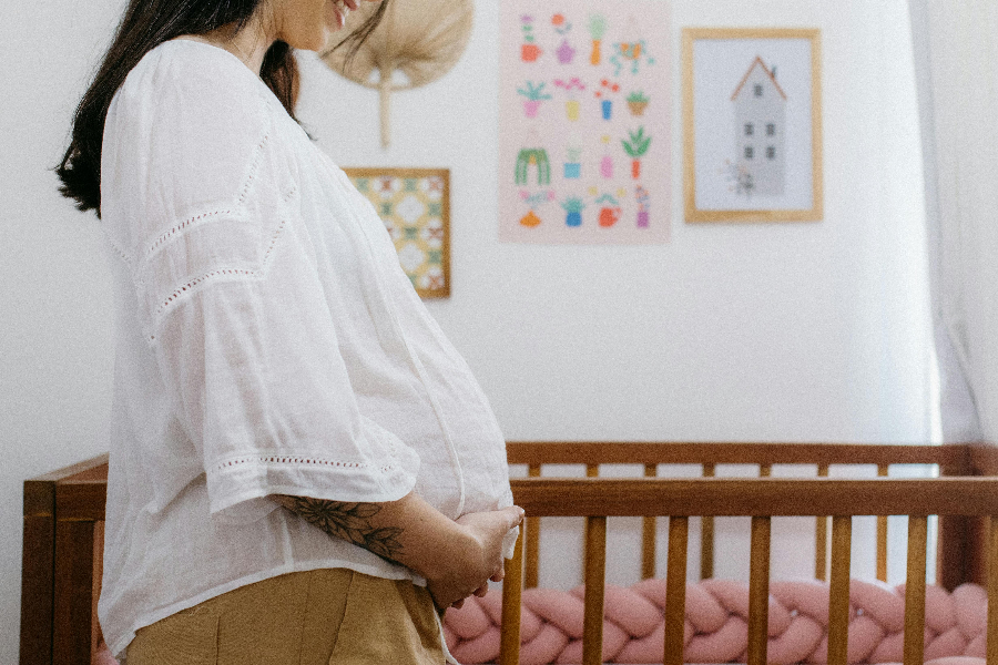 Pregnant person standing in a nursery.