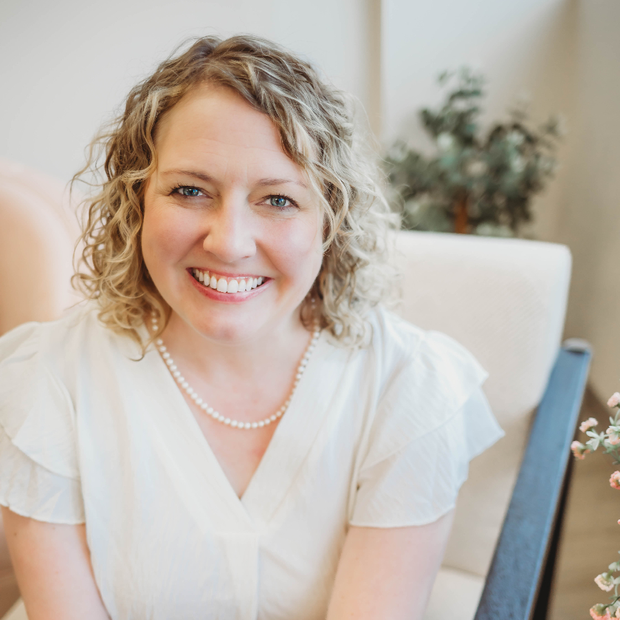 Blonde woman in a white top smiling.
